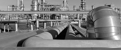 Rohrleitungssystem und Industriegebäude im Hintergrund, verzweigte Rohre für den Transport chemischer Stoffe.