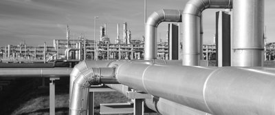 Außenbereich einer Industrieanlage mit komplexem Netz aus Rohren und Leitungen für Gas- oder Flüssigkeitstransporte.